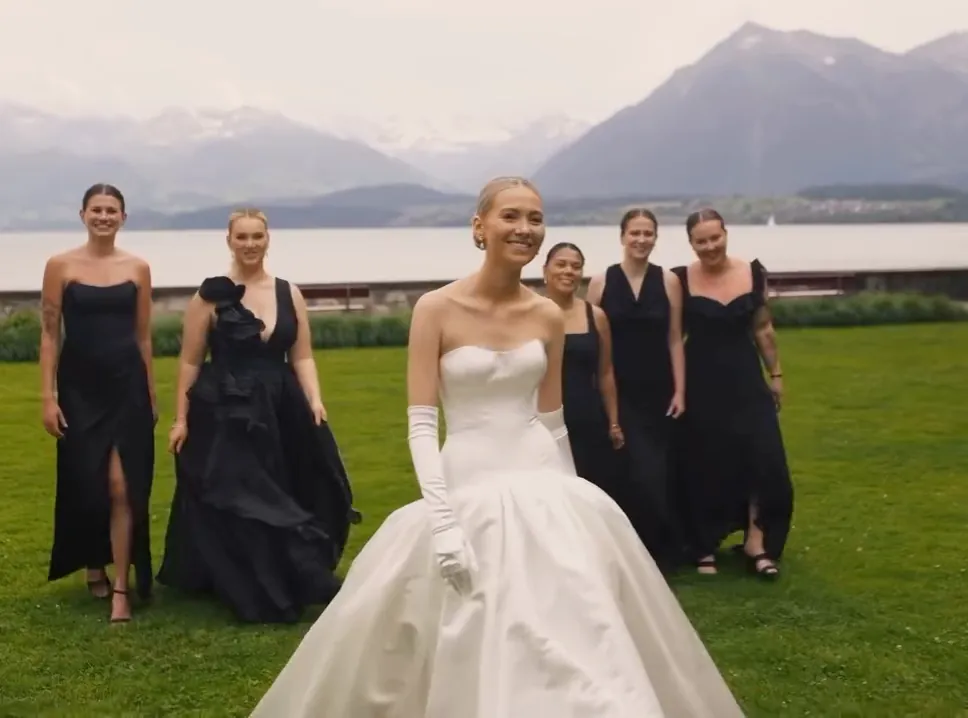 Bride on a château lawn with an alpine lake and mountains behind her.