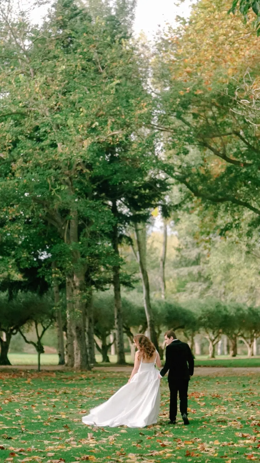 Couple walking through an autumn park after their outdoor ceremony.