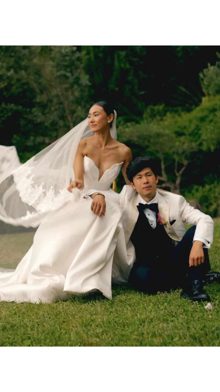 Couple on an open lawn with the bride’s veil lifting in the wind.